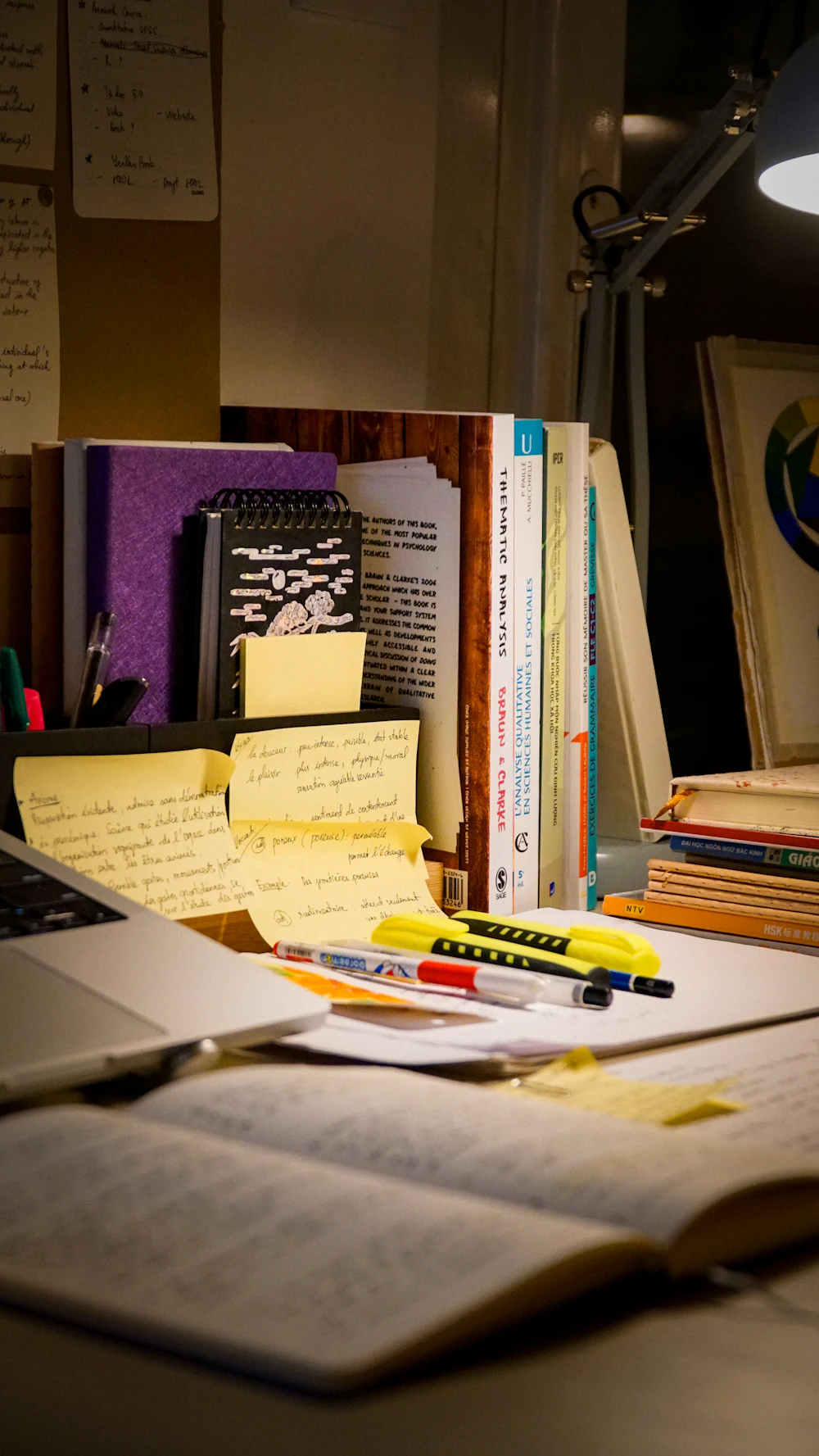 Desk with research books, notes and a laptop